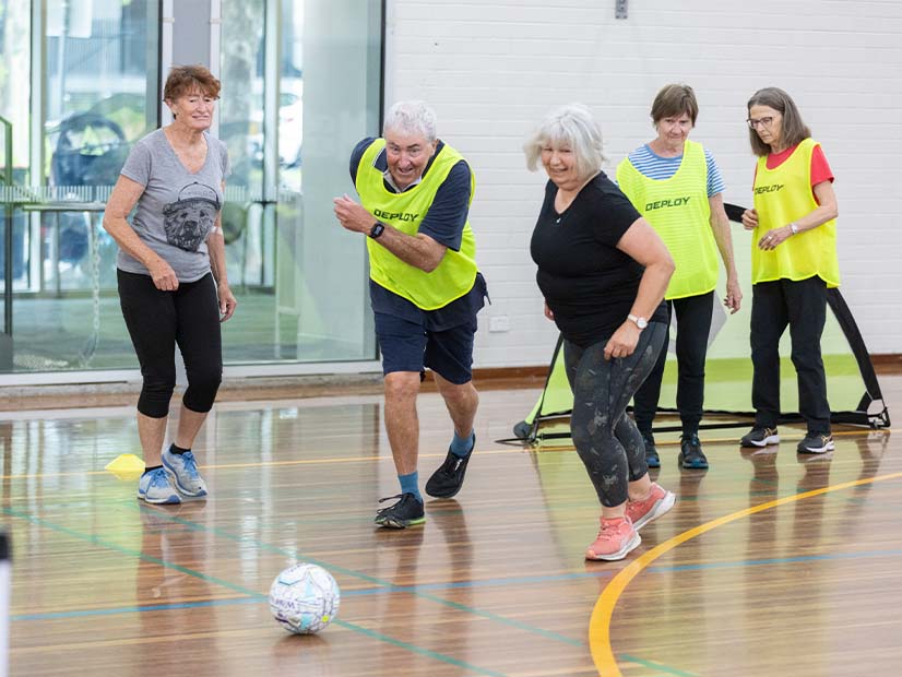Participants playing walking football in stadium