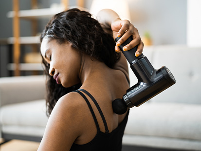 Woman using massage gun on her back